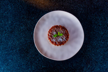 A delectable dessert tart is artfully arranged on a white plate and adorned with fresh mint.