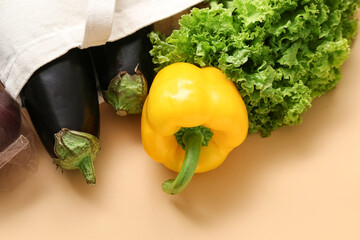 Eco bag with different fresh vegetables on beige background, closeup