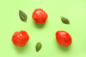 Fresh ripe tomatoes and basil on green background