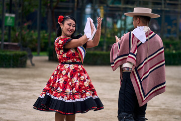 Portrait of a smiling young couple dressed as Chilean huasos, posing and joyfully dancing cueca...