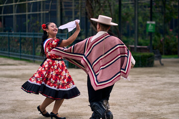 Portrait of a smiling young couple dressed as Chilean huasos, posing and joyfully dancing cueca...
