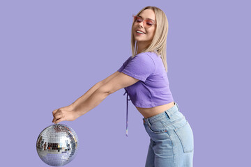 Beautiful young woman with disco ball on purple background