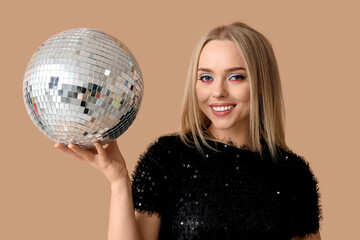Beautiful young woman with disco ball on brown background