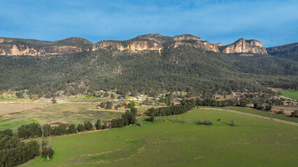 Drone aerial photograph of lush agricultural farmland and vegetation along the cliff face in Capertee Valley in Wollemi National Park in the Central Tablelands of NSW, Australia.