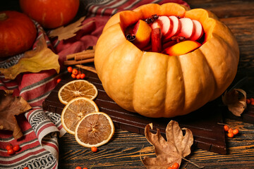 Beautiful composition with tasty mulled wine in pumpkin on wooden background