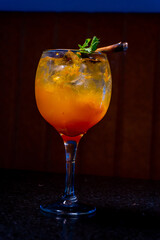 Delicious orange cocktail with mint and cinnamon in an elegant glass.