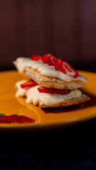 Delectable strawberry mille-feuille dessert beautifully presented on a yellow plate.