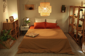 Interior of cozy bedroom with shelf units and glowing lamps at night