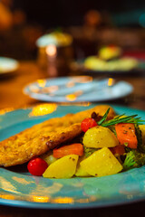 A beautifully presented plate of fried fish served with fresh, colorful vegetables.
