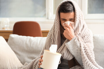 Sick little boy with plaid and tissue sneezing at home