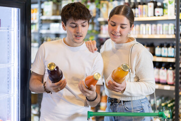 Couple in love chooses natural juices in an eco supermarket. Woman and a man buy sugar-free juices...