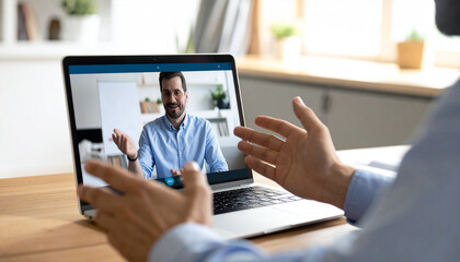 Virtual Business Discussion: An individual engages in a video call on a laptop, actively participating in a business discussion in a modern work setup, symbolizing virtual communication.