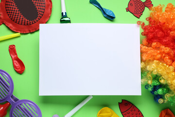 Blank card with paper fishes, whoopee cushion and party decor on green background. April Fools Day...