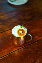 Delicious cocktail served in a copper mug, garnished with a dried orange slice and whipped cream.