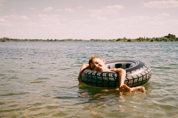 teenage boy swimming on inflatable ring on lake, holiday concept