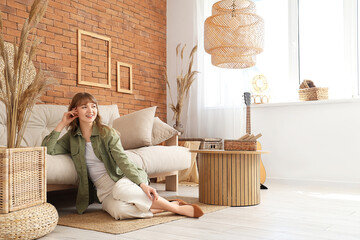 Young pretty woman resting on floor near sofa in beautiful living room