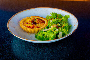 A delicious quiche is served with a fresh salad on a plate, ready to eat.