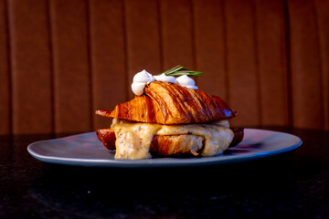 A beautifully plated croissant sandwich with sauce and cream, ready to eat.