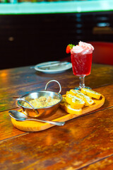 A vibrant cocktail and garlic bread set on a wooden table, ready to be enjoyed.