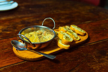 Creamy dip served with garlic bread on a wooden platter, perfect for sharing and enjoying.