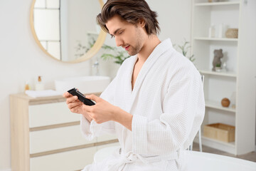 Young bearded man with trimmer in bathroom