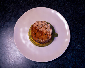 Delicious mini chocolate cake with creamy topping presented on a white plate.