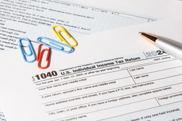 A U.S. tax document Form 1040 is placed neatly on a desk alongside a pen, representing the annual...