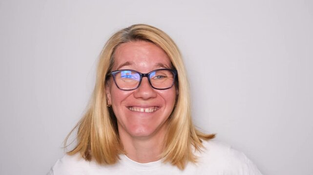 Young woman or mom playfully sticks out her tongue, showing a silly face close-up. Her expression is light-hearted and fun, capturing a candid and humorous moment in front of the camera