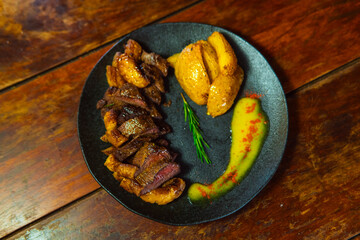 A beautifully presented plate of steak, roasted potatoes, and a vibrant sauce, ready to be enjoyed.