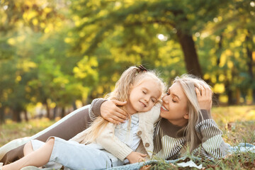 Fototapeta premium Little girl with her mother lying in park on autumn day