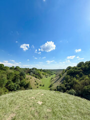 From the crest of Zagajicka Brda, rolling loess hills and a remote green valley stretch beneath a vast summer sky in northern Serbia Deliblatska Sands special nature reserve.