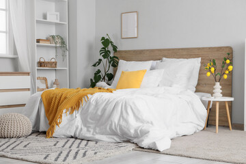 Interior of light bedroom with shelf unit, tree branches and lemons in vase