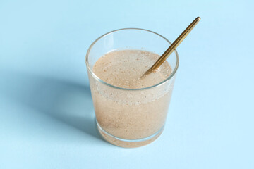 Glass of water with psyllium husk on light blue background