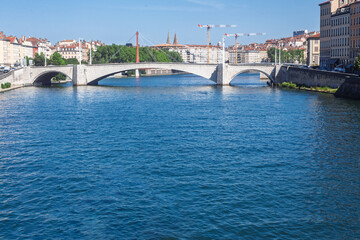 Pont Bonaparte bridge of Saone river near the Quais de Saone riverbank and riverside in the city center of Lyon and Fourviere hill towers under clear summer sky.