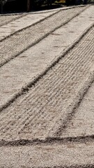 Vertical image of raked sand paths outdoor in a Japanese Zen garden at daytime at the Higashiyama Jisho-ji temple in Kyoto in Japan with space for text.