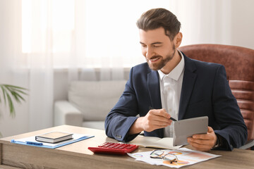 Male bank manager working with calculators in office