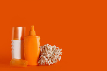 Composition with coral and bottles of sunscreen cream on orange background