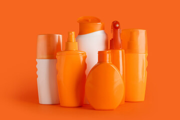 Composition with different bottles of sunscreen cream on orange background