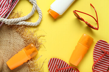 Frame made of bag, hat, flip-flops, bottles of sunscreen cream and sunglasses on yellow background