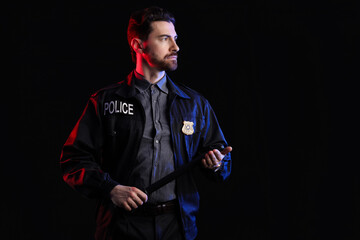 Male police officer with baton on black background