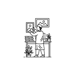 Person arranging artwork in creative workspace with plants and shelves
