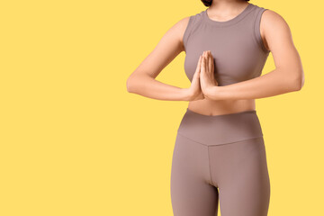 Sporty young woman doing yoga on yellow background