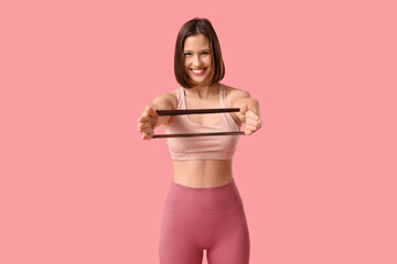 Sporty young woman with stretching band on pink background