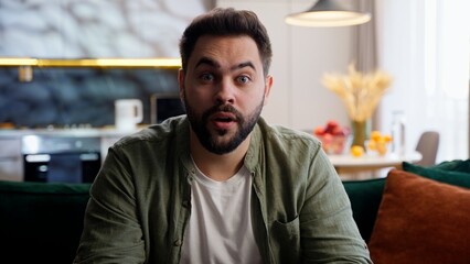 Obraz premium Shocked amazed excited Caucasian European model man male guy homeowner businessman customer client looking at camera gesturing shock wow open mouth wonder excitement indoor living room home apartment
