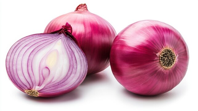 Close up of two whole red onions and one halved onion on a white surface in a studio setting