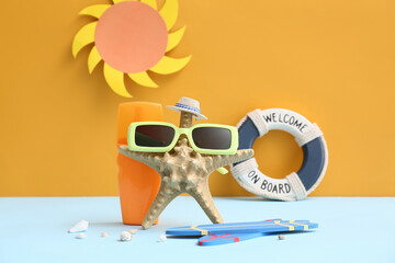 Starfish, bottle of sunscreen cream and beach accessories on color background
