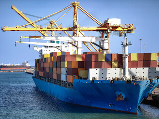 Large cargo ship docked at a busy port, loaded with colorful containers and surrounded by massive...