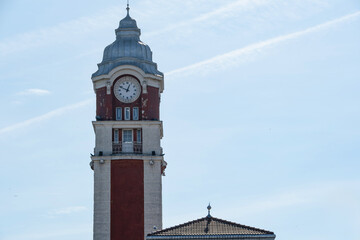 Old station clock tower with a distinctive domed roof stands tall against a bright blue sky