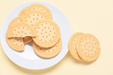Plate with sweet cookies on yellow background