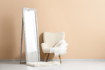 Floor mirror and armchair near beige wall in interior of room